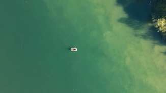 Ein Gummiboot wurde von oben fotografiert. Der Rhein schimmert in blau bis grünen Farben.