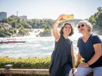 Freudinnen am Rheinfal Zwei Freundinnen machen ein Selfie mit dem Rheinfall, dem grössten Wasserfall Europas , im Hintergrund.