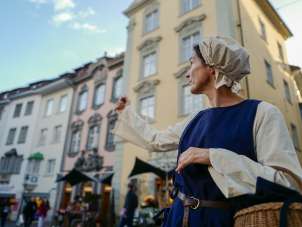 Krämerin Schaffhausen Führung Die als Krämerin verkleidete Person zeigt mit ihrem Arm auf eine Sehenswürdigkeit.