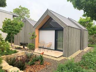 Ein kleines Haus, das an ein modernes Räbhüüsli erinnert, wurde zur Übernachtungsmöglichkeit umgebaut. Vor dem Hüüsli hat es eine kleinen Sitzplatz.