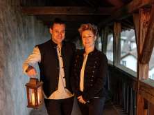 Eine Frau und ein Mann auf einer Festung. Der Mann hält eine Laterne.