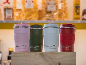To-Go Becher in den Farben rosa, olivgrün, weiss und rot haben eine silbrige Gravur der Schaffhauser Skyline und darunter steht "Schaffhausen".