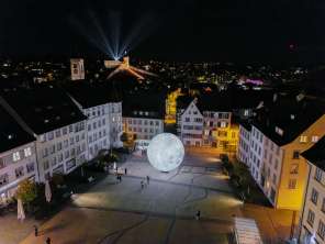 Blick von Oben in der Nacht auch den beleuchteten Munot. Lichtstrahlen leuchten in den Nachthimmel.