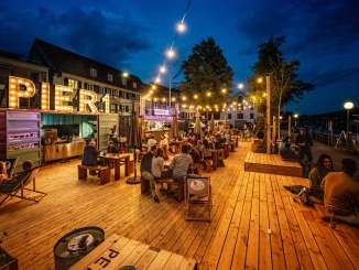 Auf einem Holzpodest wurde ein Pop-Up Café und bar eingerichtet. Das Essen wir aus umfunktionierten Containern serviert.