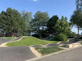 Pumptrack-Anlage Stetten Eine Pumptrack Anlage ist umgeben von Bäumen.