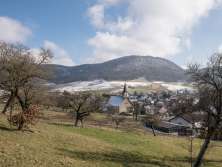 Man blickt von einer leichten Erhöhung auf ein Klines Dorf. Wenige stellen sind noch mit Schnee bedeckt.