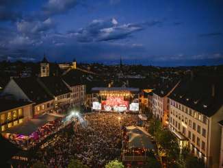 Stars in der Stadt Ein Platz zwischen Häuser in der Altstadt. Der Platz ist gefüllt mit Menschen. Vorne Befindet sich eine Bühne mit der Aufschrift "Stars in Town".