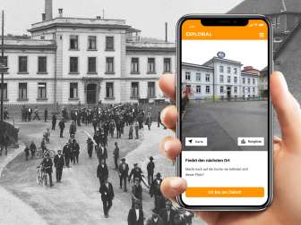 Explorial Neuhausen am Rheinfall Eine Hand hält ein Handy vor einem schwarz weiss Bild. Auf dem Handy sieht man das Gebäude, wie es heute aussieht.