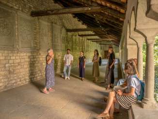 Eine Gruppe von Menschen steht im Kreuzgang zu Allerheiligen in Schaffhausen. Die Menschen hören einer Person gespannt zu.