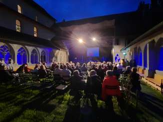 nordArt Festival Stein am Rhein In einem Innenhof auf dem Rasen befindet sich eine Bestuhlung. Eine provisorische Bühne ist aufgebaut. Ca. 50 Personen befinden sich im Publikum.