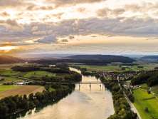 Rhein und Landschaft bei Hemishofen von oben während dem Sonnenuntergang. Über den Rhein führt eine Brücke.