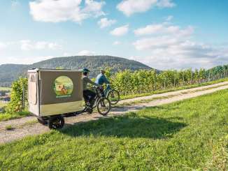 Velosafari Schaffhauserland Zwei Freudinnen sind mit den E-Bike in den Reben unterwegs. Bei einem Cargovelo hat es einen ausklappbaren Zeltaufbau.
