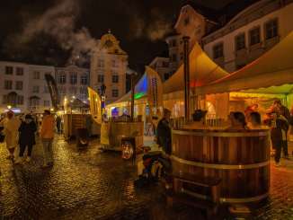Auf einem Platz in der Altstadt am Abend herrscht reges Treiben. In mehreren Hotpots entspannen Wellnessfans.
