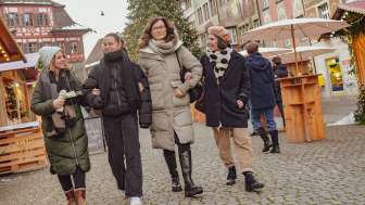 Vier Freundinnen tragen warme Winterkleidung und laufen über einen Platz. Im Hintergrund die Steiner Altstadt mit Fassadenmalereien.