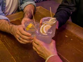 Drei Personen stossen mit einem Gin-Tonic an.