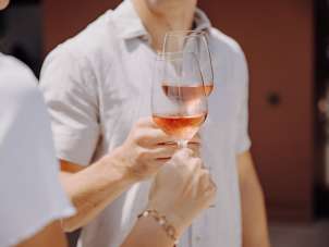 Zwei Personen stossen mit einem Glas Rosé an.