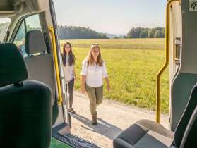 Randenbus Hemmental Von innen eines Kleinbus sieht man, wie zwei Personen zum Bus laufen.