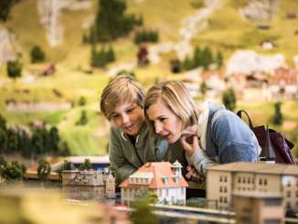 Eine Mutter ist mit Ihrem Sohn in der Miniaturwelt Smilestones. Sie schauen gerade Häuser an.