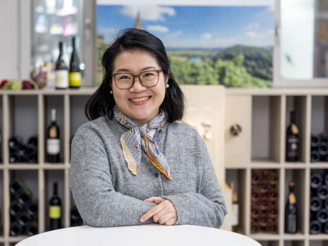 Portrait Anna Chen. Die Frau hat schwarze mittellange Haare, trägt eine Brille und ein Tuch um den Hals.