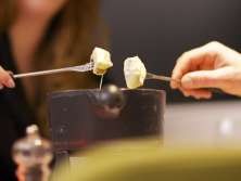 Zwei Personen essen Fondue und tunken gleichzeitig ihr Brot in den Käse.